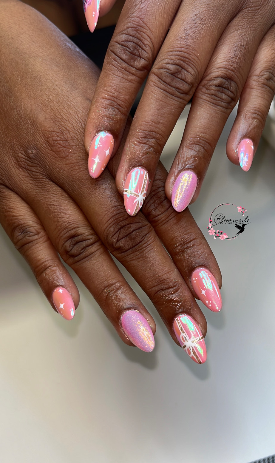Ongles roses nacrés avec reflets holographiques et motifs blancs, réalisés chez Bloominails à La Réunion